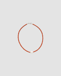 a single baroque pearl floats on a red bead necklace