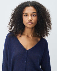 Woman wearing a navy blue long-sleeve knit cardigan from American Vintage  against a light grey background