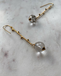 Long gold drop earrings with clear quartz available at The Pared Store