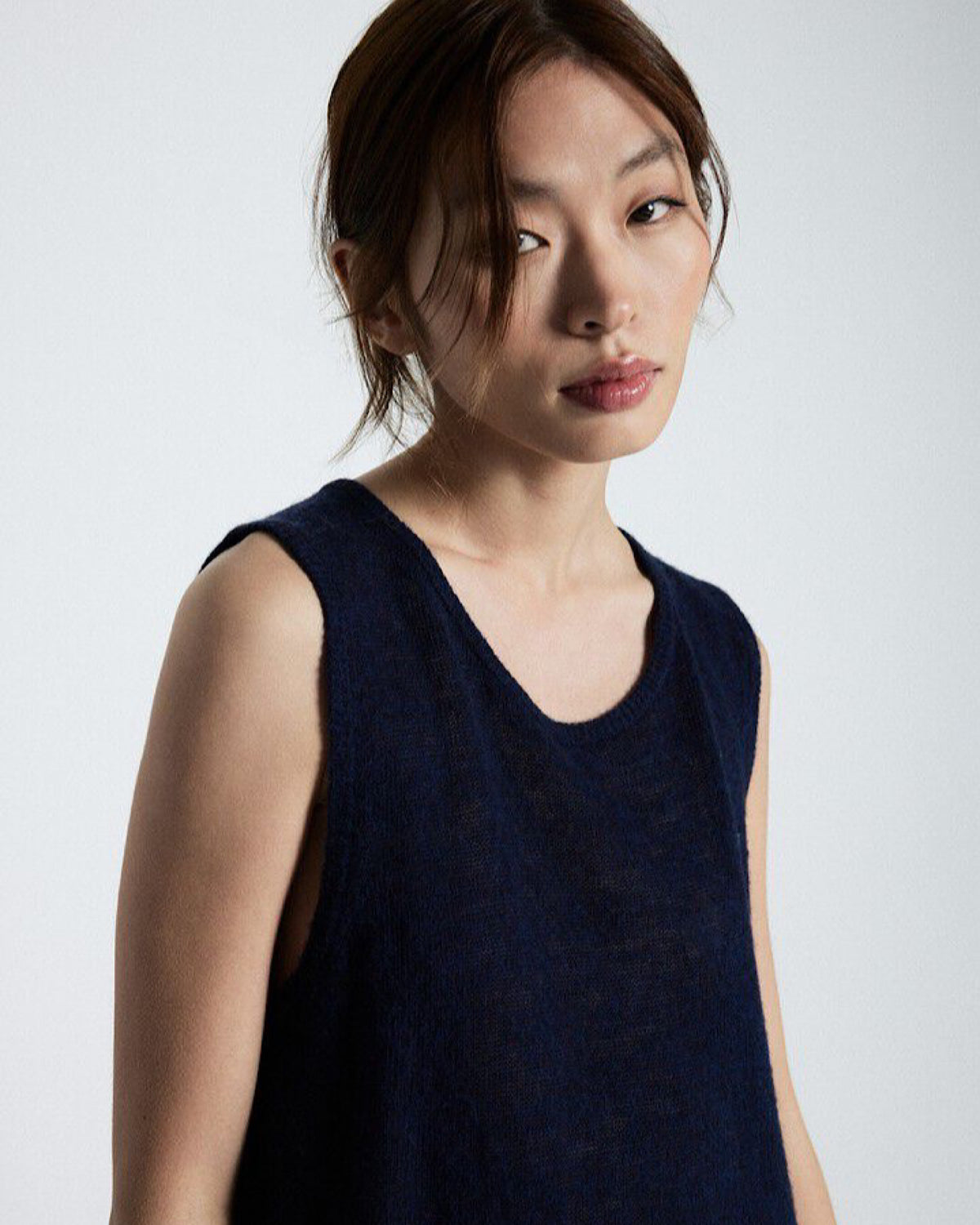 Woman wearing a dark blue sleeveless top against a white background