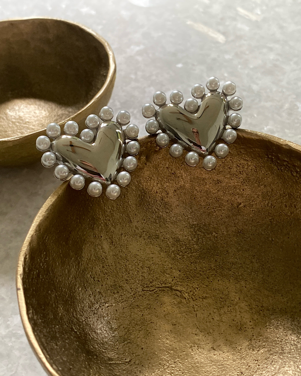 Silver and pearl heart earrings in a bowl