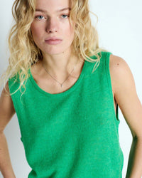 Woman wearing a green sleeveless top against a white background