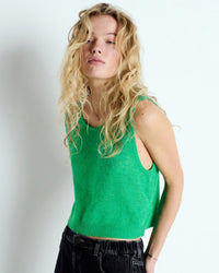 Woman wearing a green sleeveless top from American Vintage with a plain background