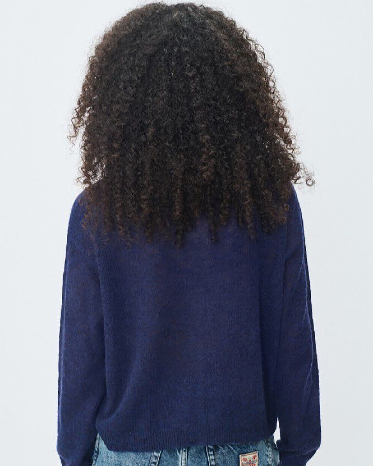 Person wearing a blue sweater with a plain background
