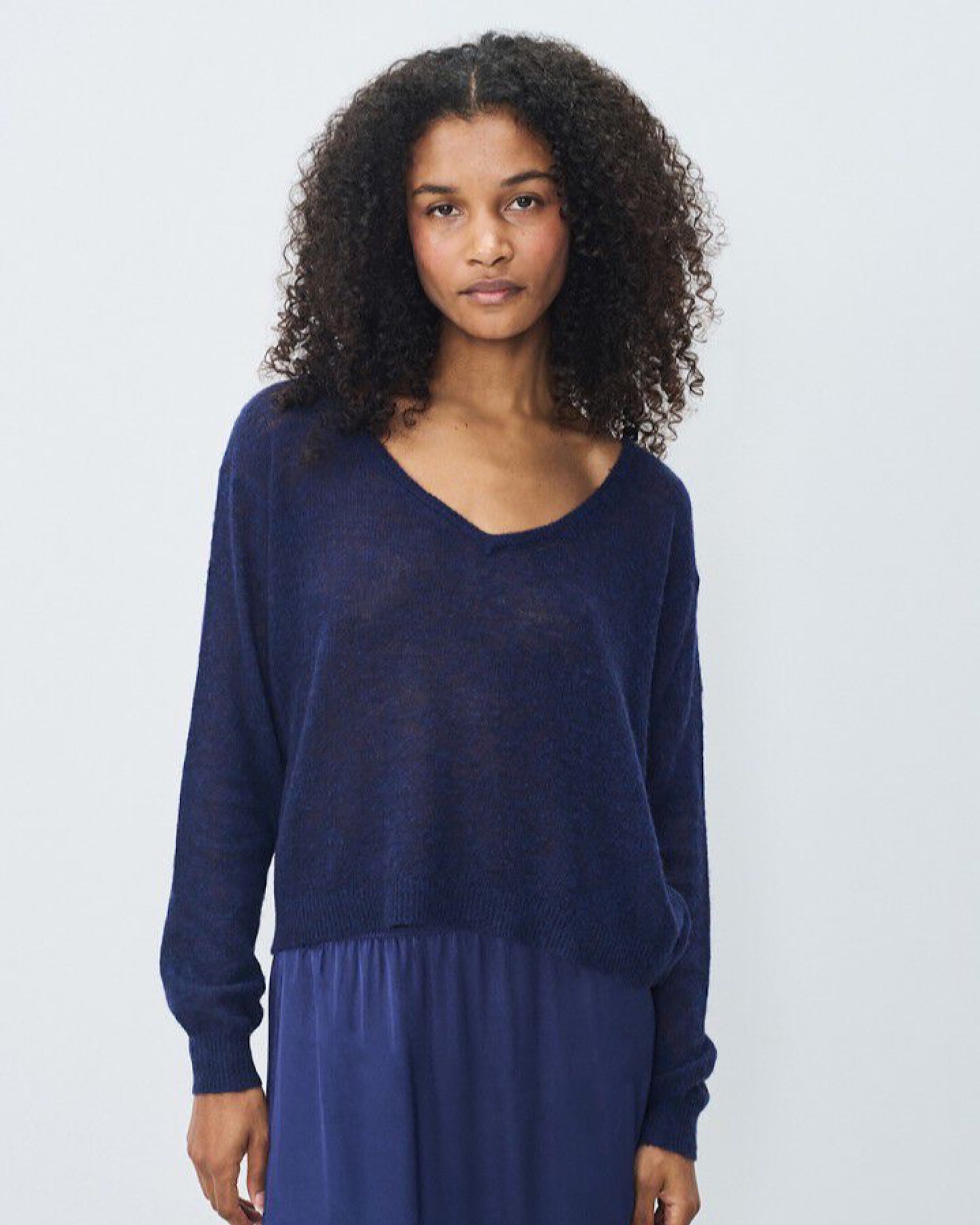 Woman wearing a lightweight knit blue sweater and skirt set against a plain background
