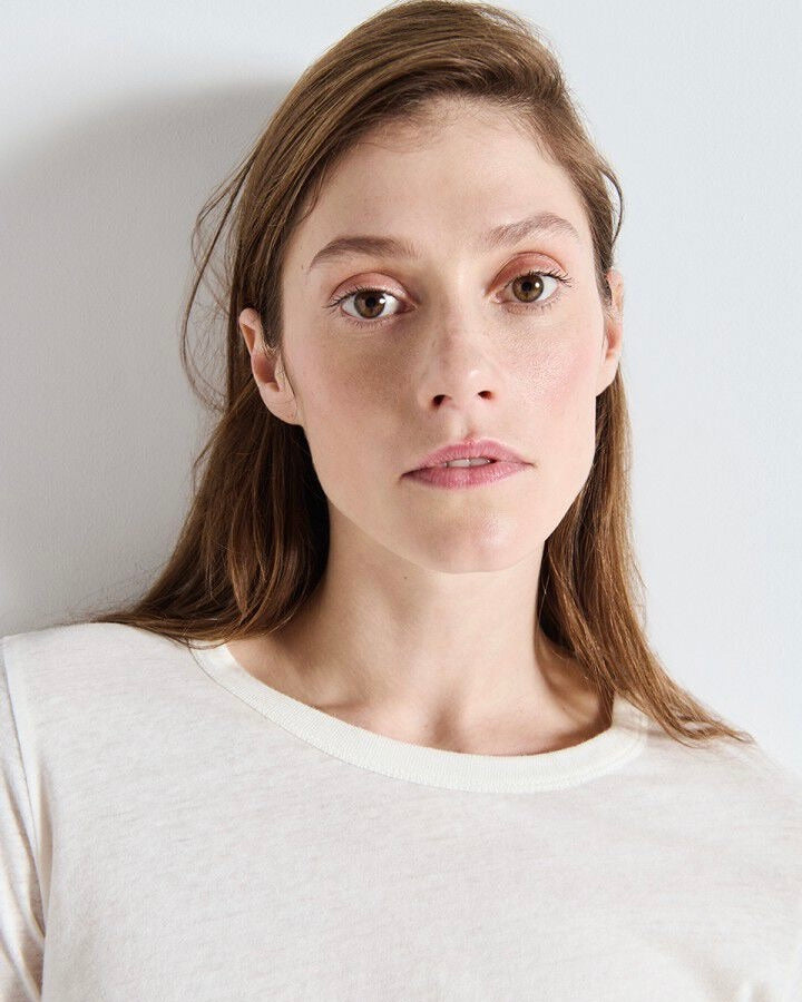 Woman wearing a light-colored top against a plain background