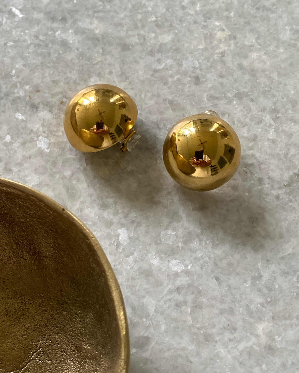 Gold clips on earrings on a marble table