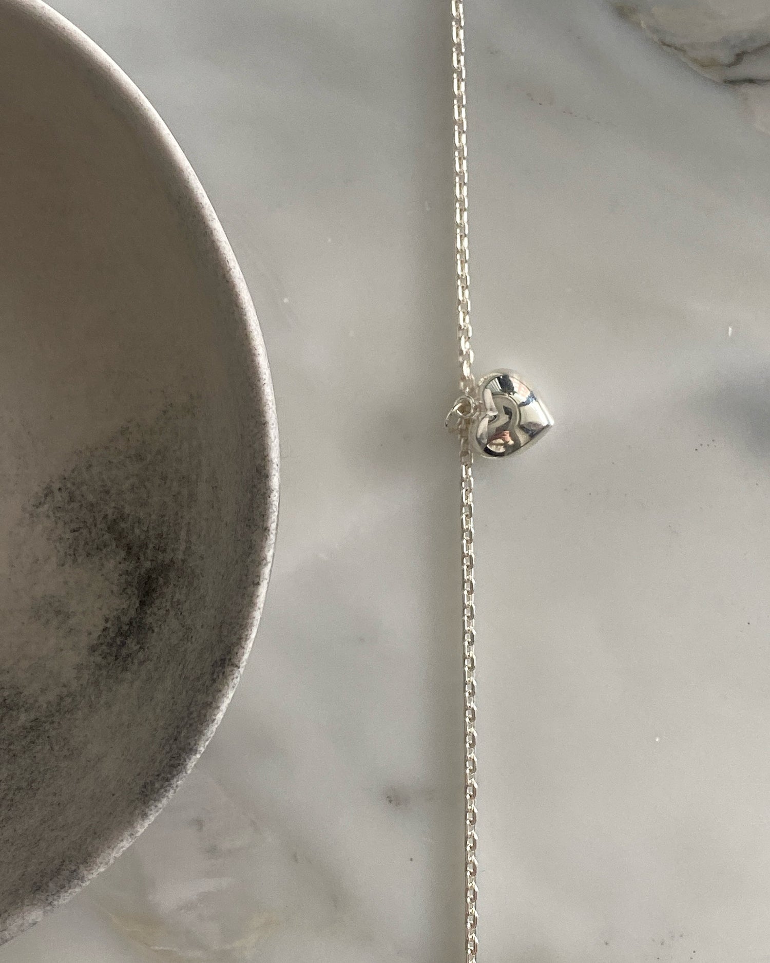 Small heart charm sits on a silver anklet chain. Available at The Pared Store, Surry Hills