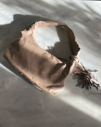 a taupe bag sits on a marble bench