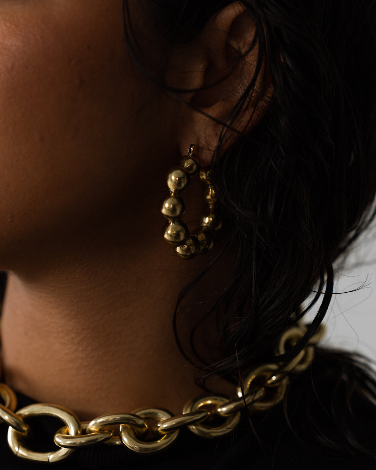 model wears hoop earrings made of joined brass balls