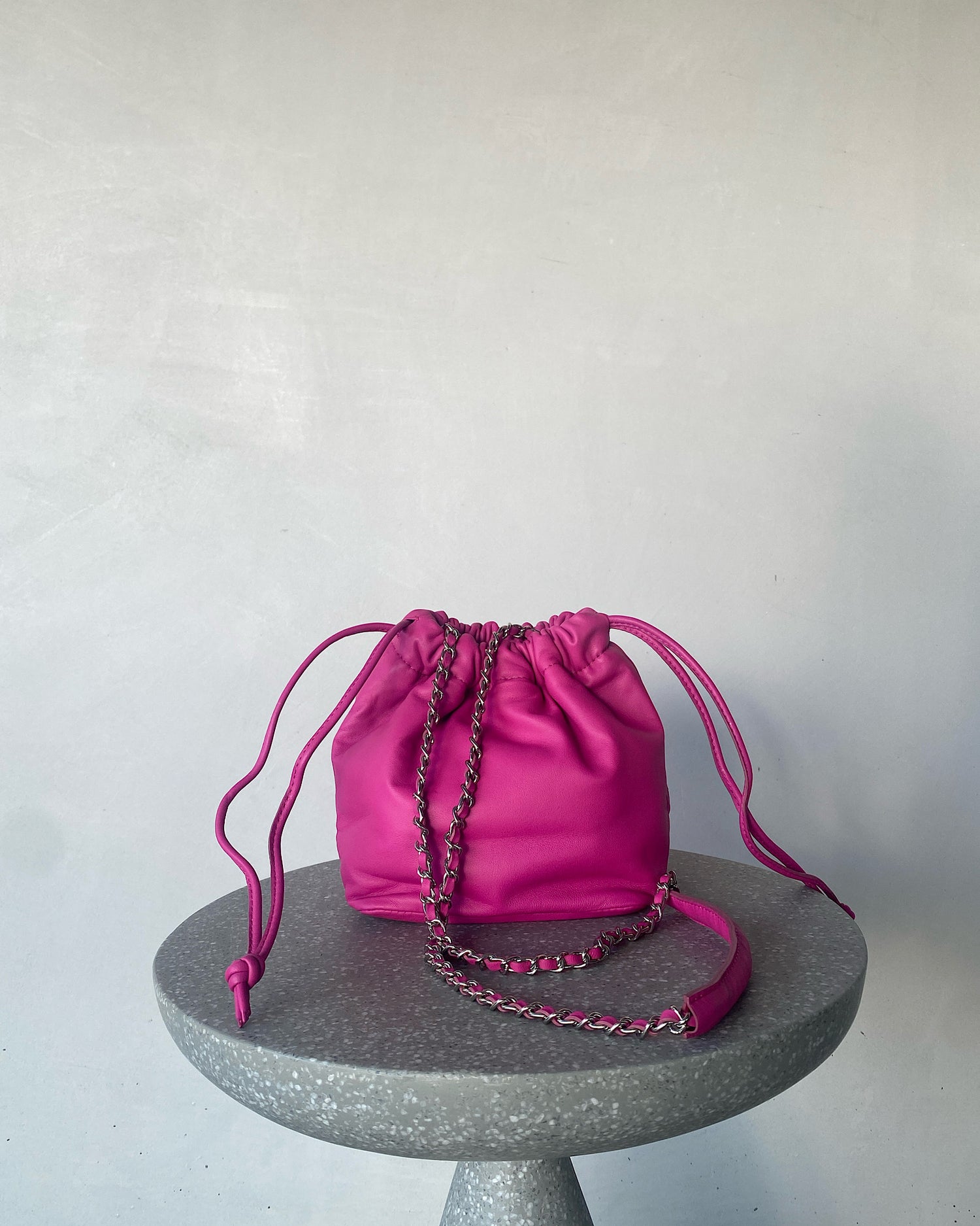 a hot pink soft leather drawstring sits on a cement base