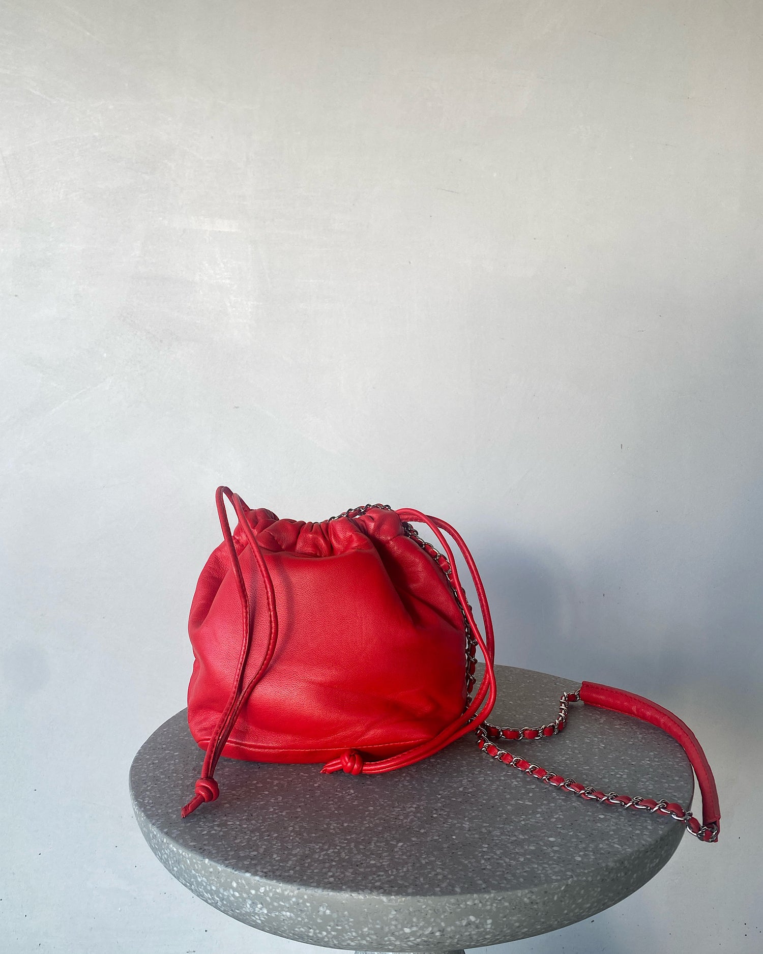 a bright red soft leather drawstring sits on a cement base