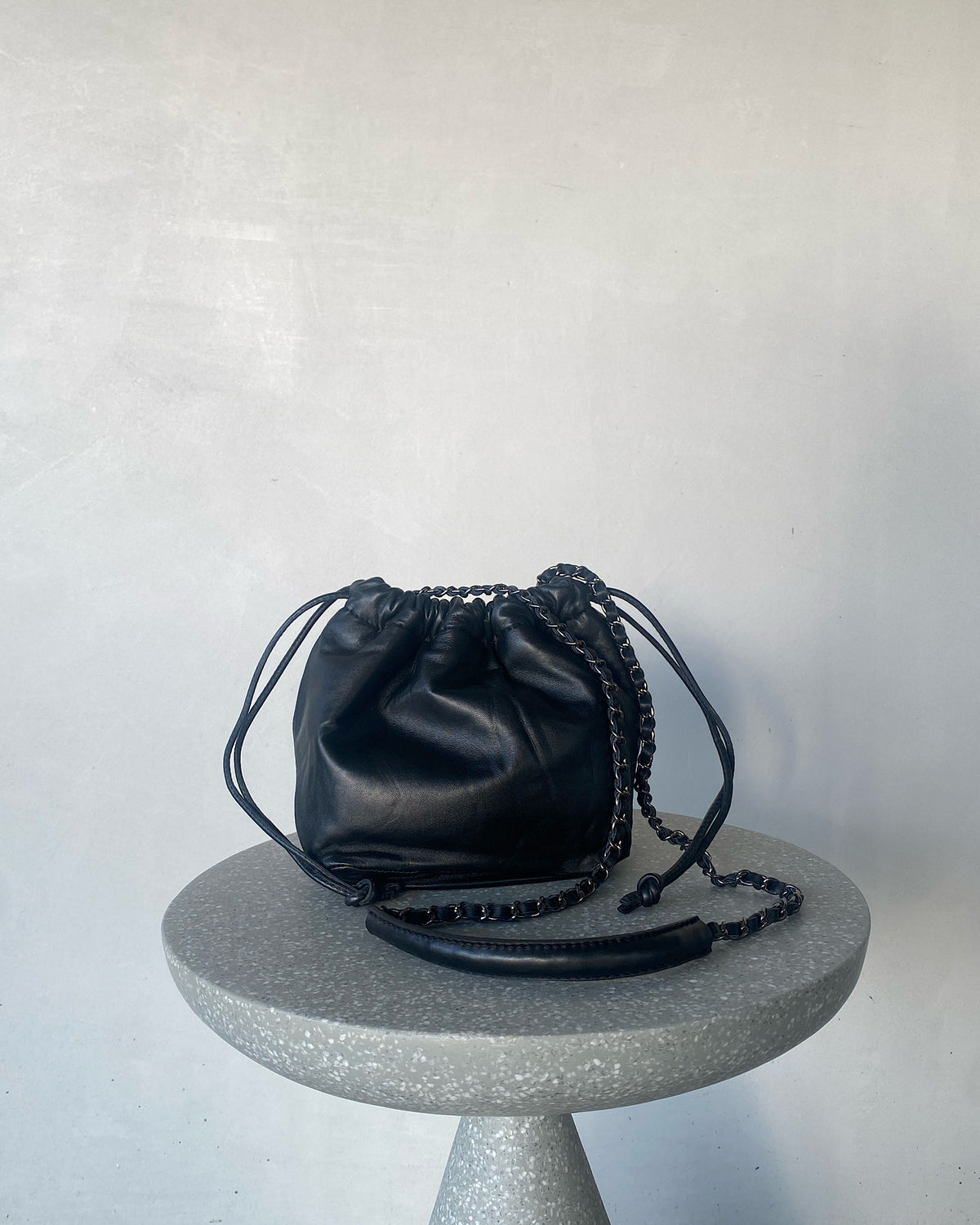 a black soft leather drawstring sits on a cement base