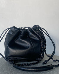 a black soft leather drawstring sits on a cement base