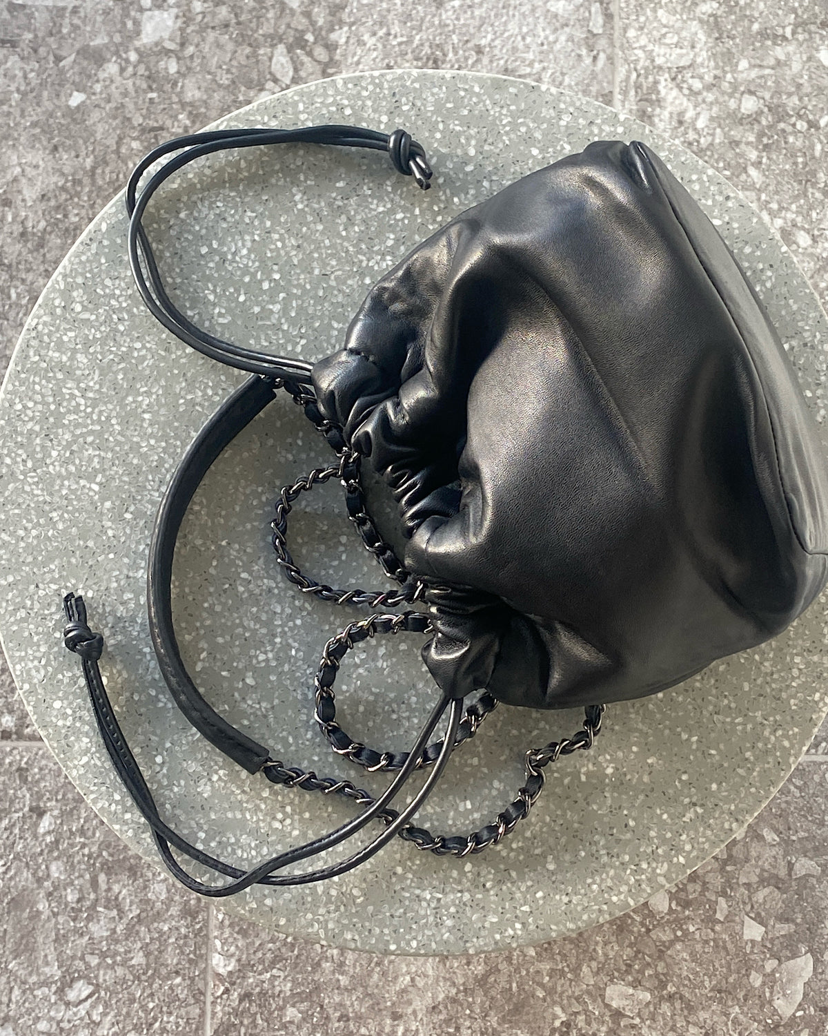 a black soft leather drawstring sits on a cement base