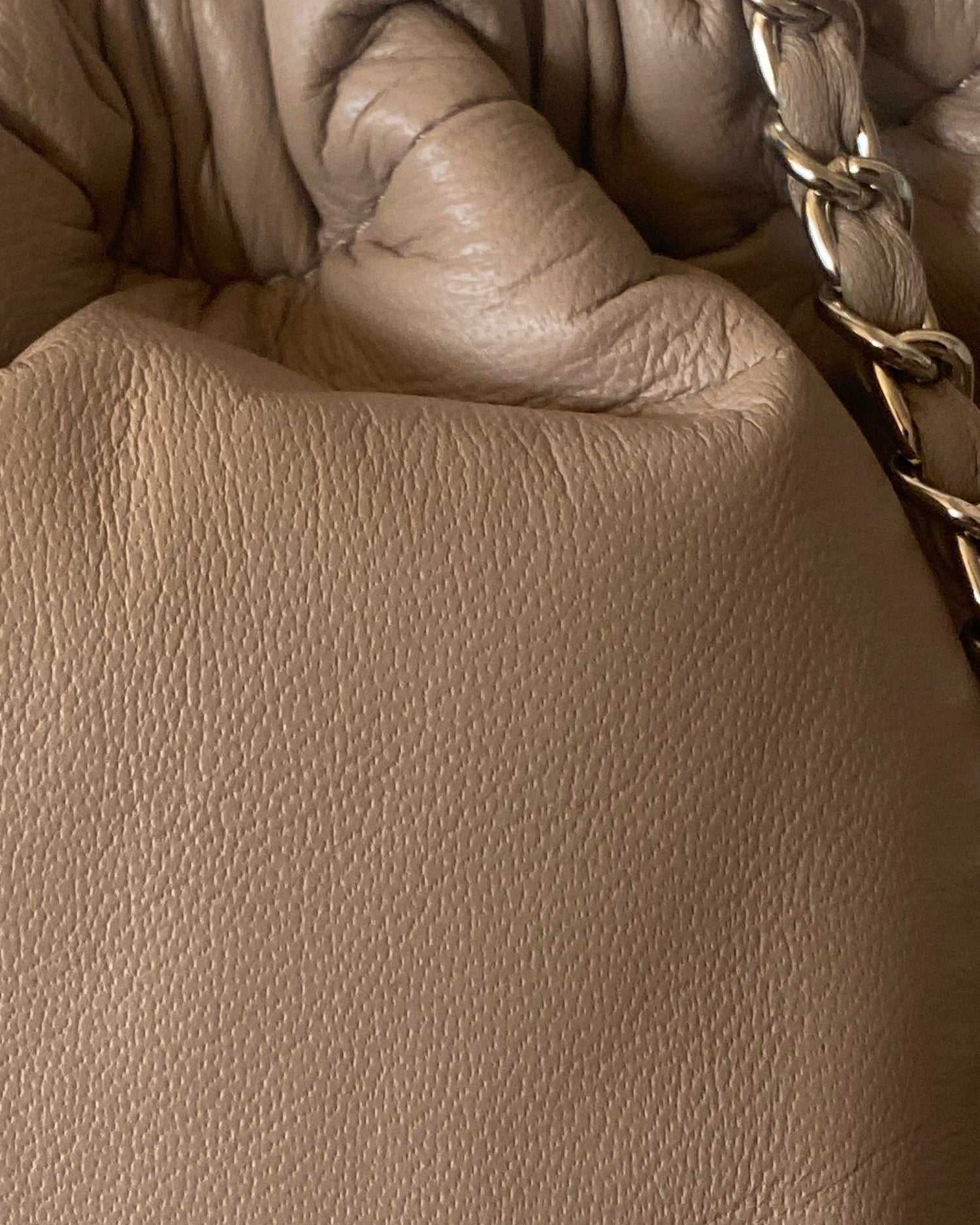 a taupe soft leather drawstring sits on a cement base