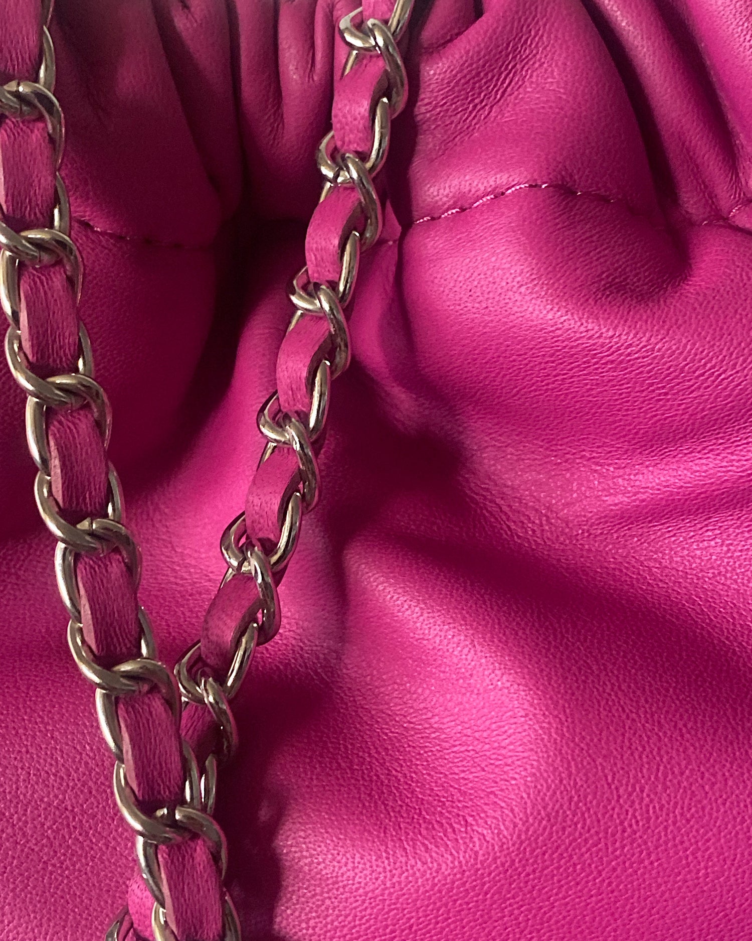 a hot pink soft leather drawstring sits on a cement base