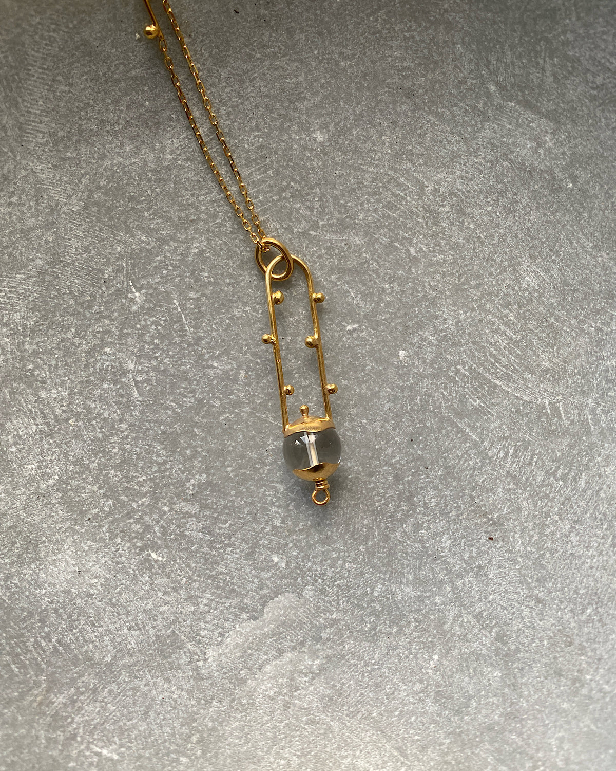 a simple open gold pendant withe a clear crystal