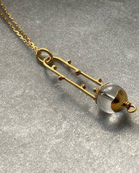 an open style gold pendant with a clear crystal