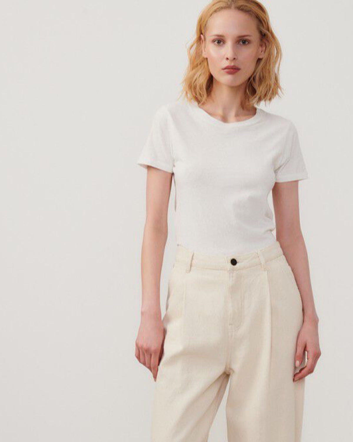 model wears a classic white short sleeve gampiy t-shirt from American vintage and cream pants