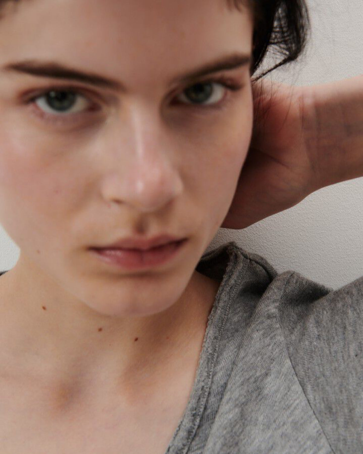 closeup of a model illustrating raw edge grey t-shirt