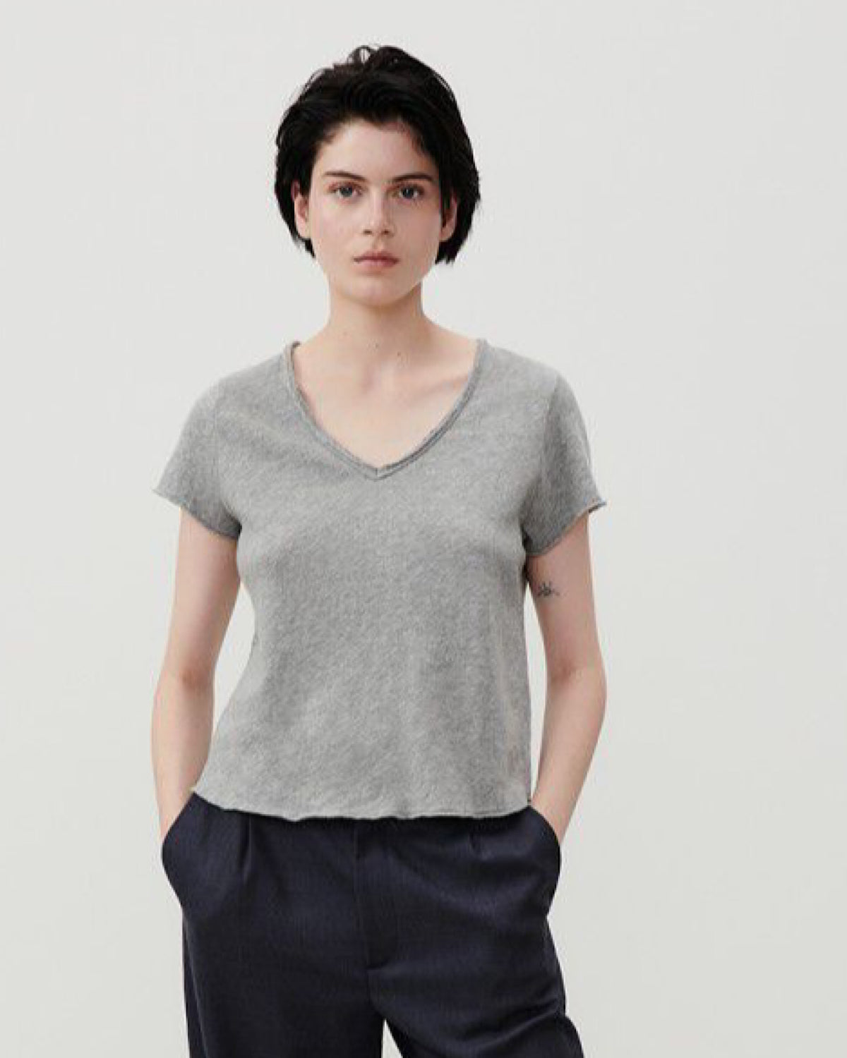 model wears a greay eraw edge V neck T-shirt wth navy pants