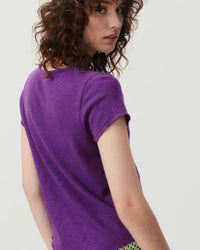 Model wears a vibrant purple v neck t-shirt from American Vintage with a raw edge finish