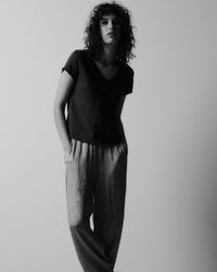 black and white images of a model wearing a dark v neck t-shirt and patterned silky pants