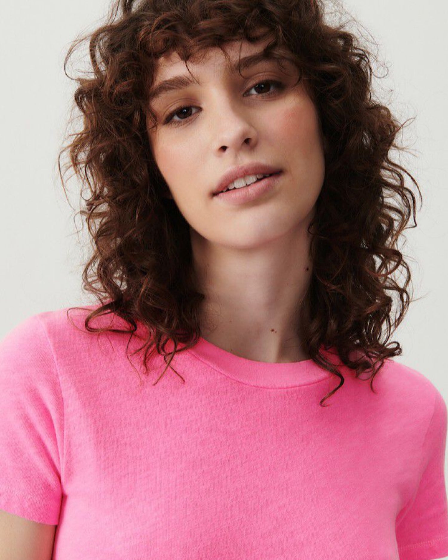 Closeup of a model wearing a bright oink fitted round neck short sleeve t-shirt from American Vintage