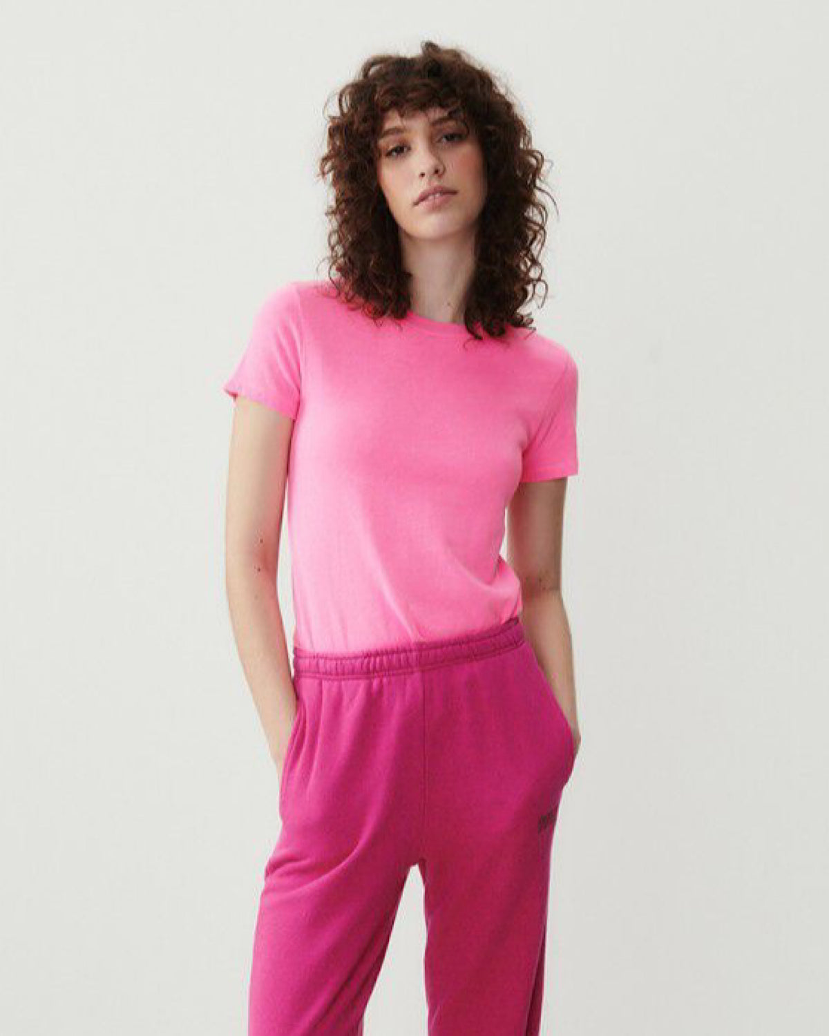 Model wearing a bright pink fitted round neck short sleeve t-shirt from American Vintage