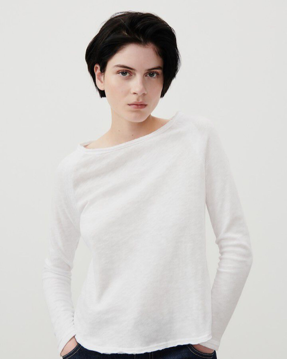 Model wears a white boast neck long sleeve t-shirt from American Vintage