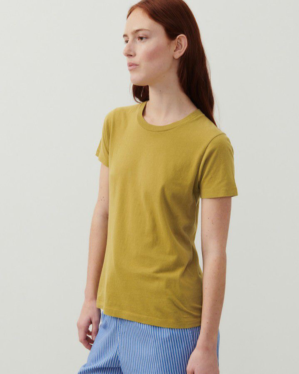 Model wears a golden hue T-shirt by American Vintage