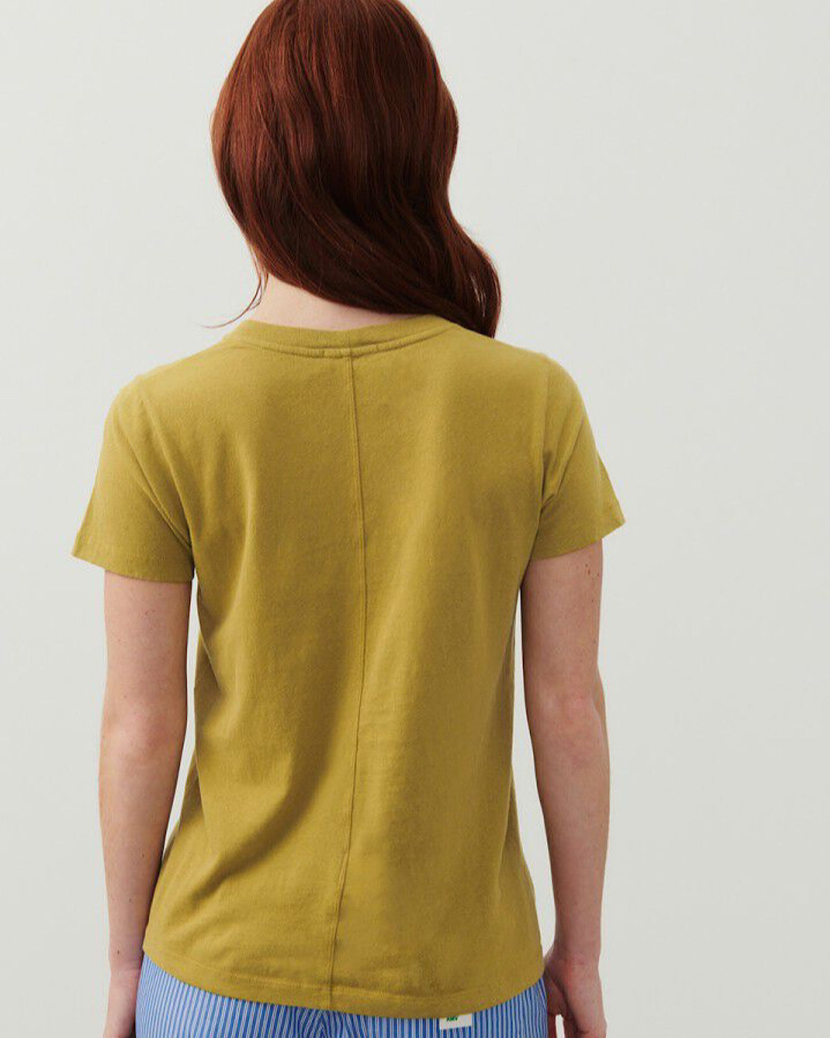 backview of a model wearing a golden coloured Gamipy T-Shirt from American VIntage and featuring a centre back seam