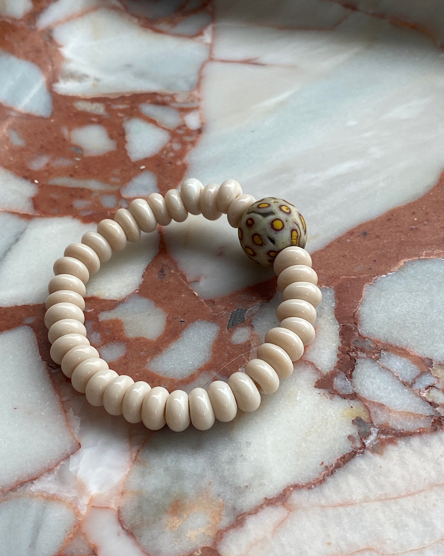 cream beaded bracelet with a central cream & yellow mottled feature bead on marble