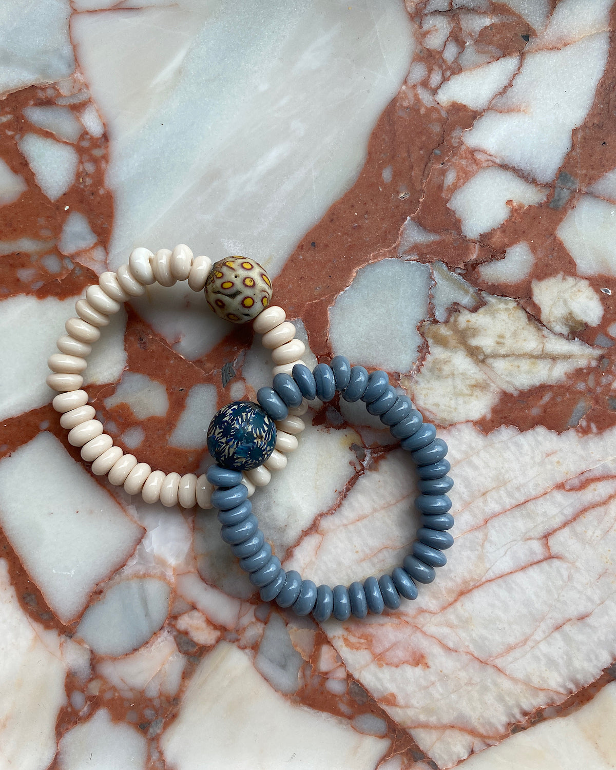 a grey and cream bracalet sit on a marble background