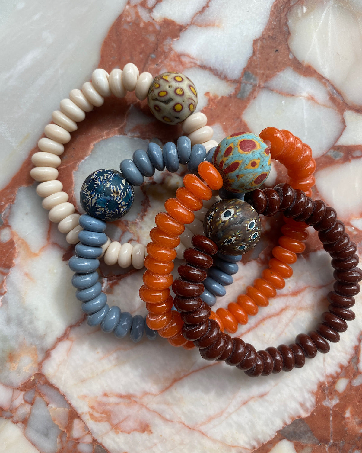 4c assorted beaded bracelets sit on a marble tray