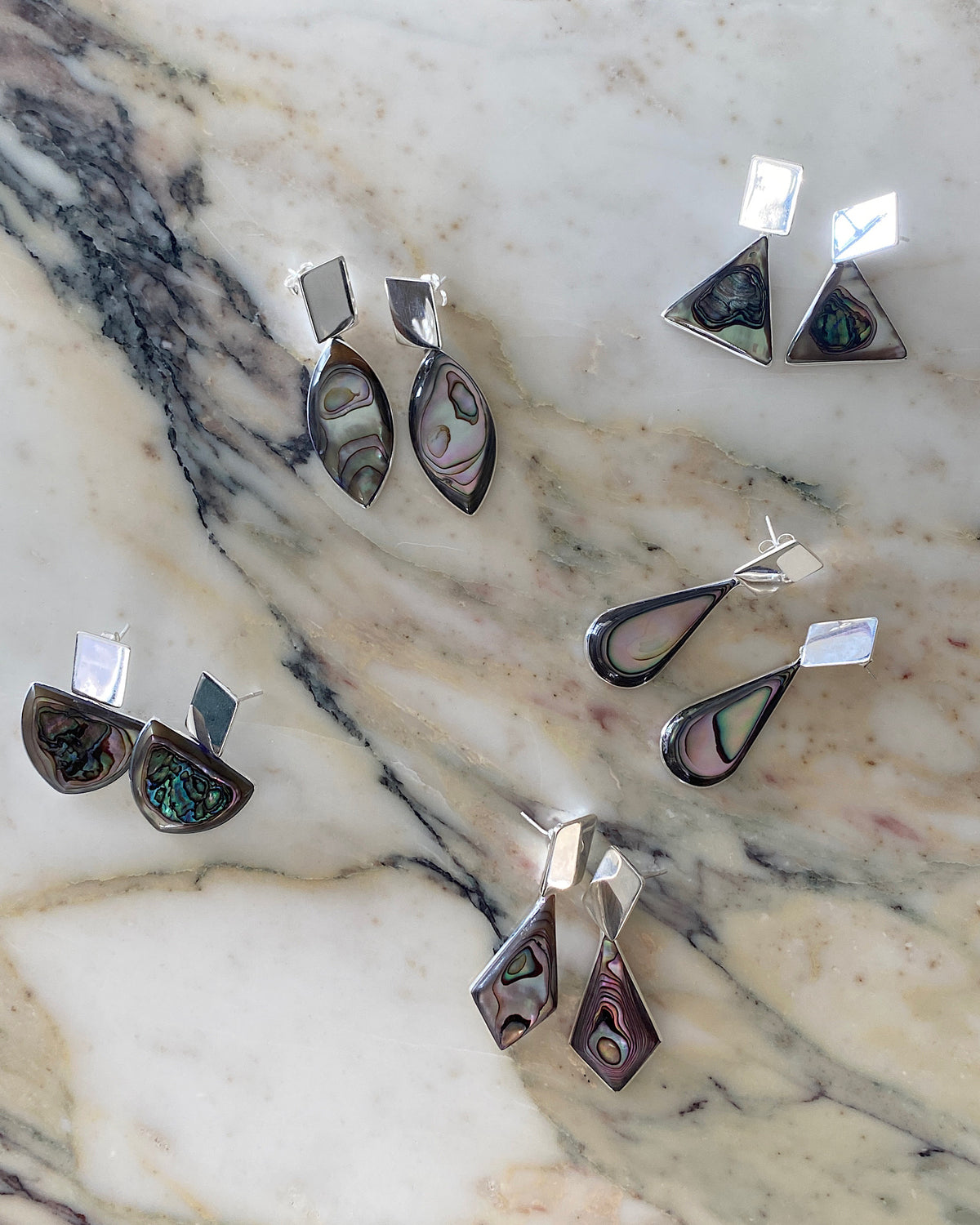 a seletion of abalone and silver earrings sit on a marble bench available in Sydney at The Pared Store