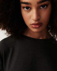 a model wears a dark grey round neck sweater