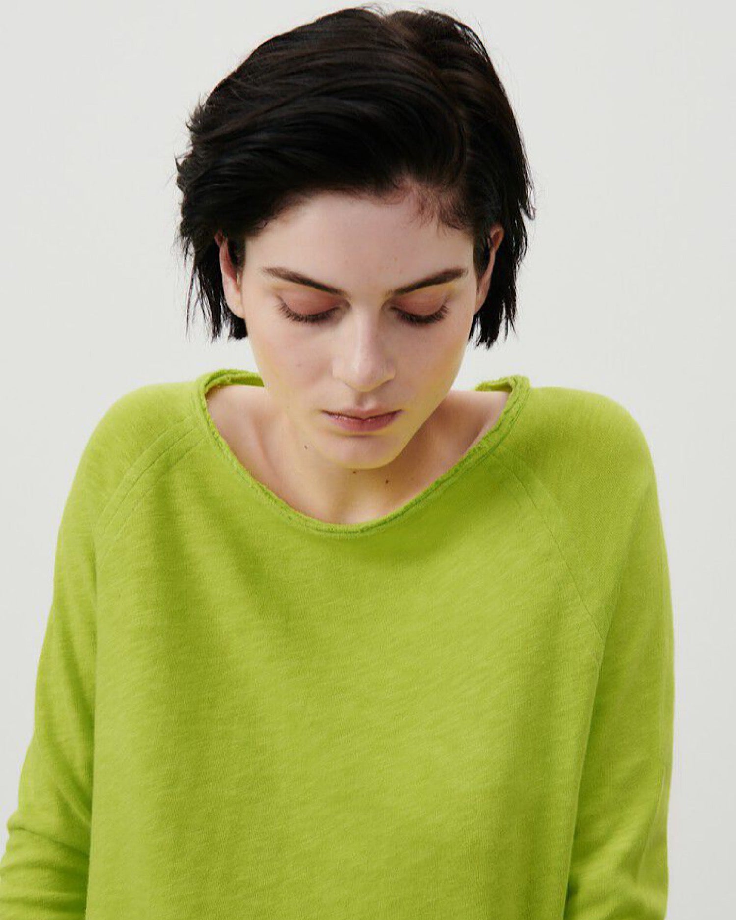 a model wears a vibrant acid green boat neck long sleeve T-shirt