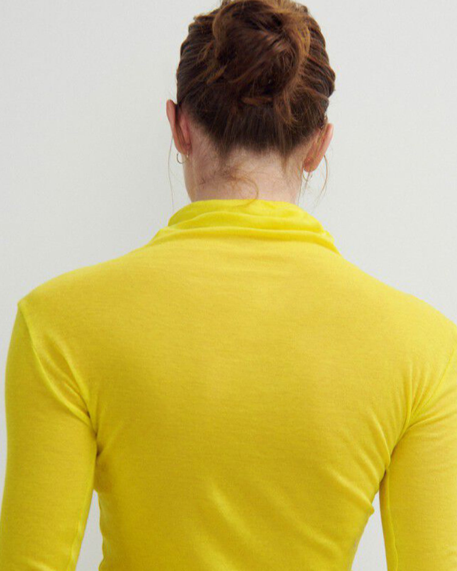 model in a bright yellow turtleneck