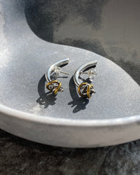 Silver bar curved earrings with mixed metal ring detail  in a bowl