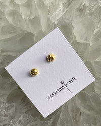 very small gold star stamped dome stud earrings sit ion their display card