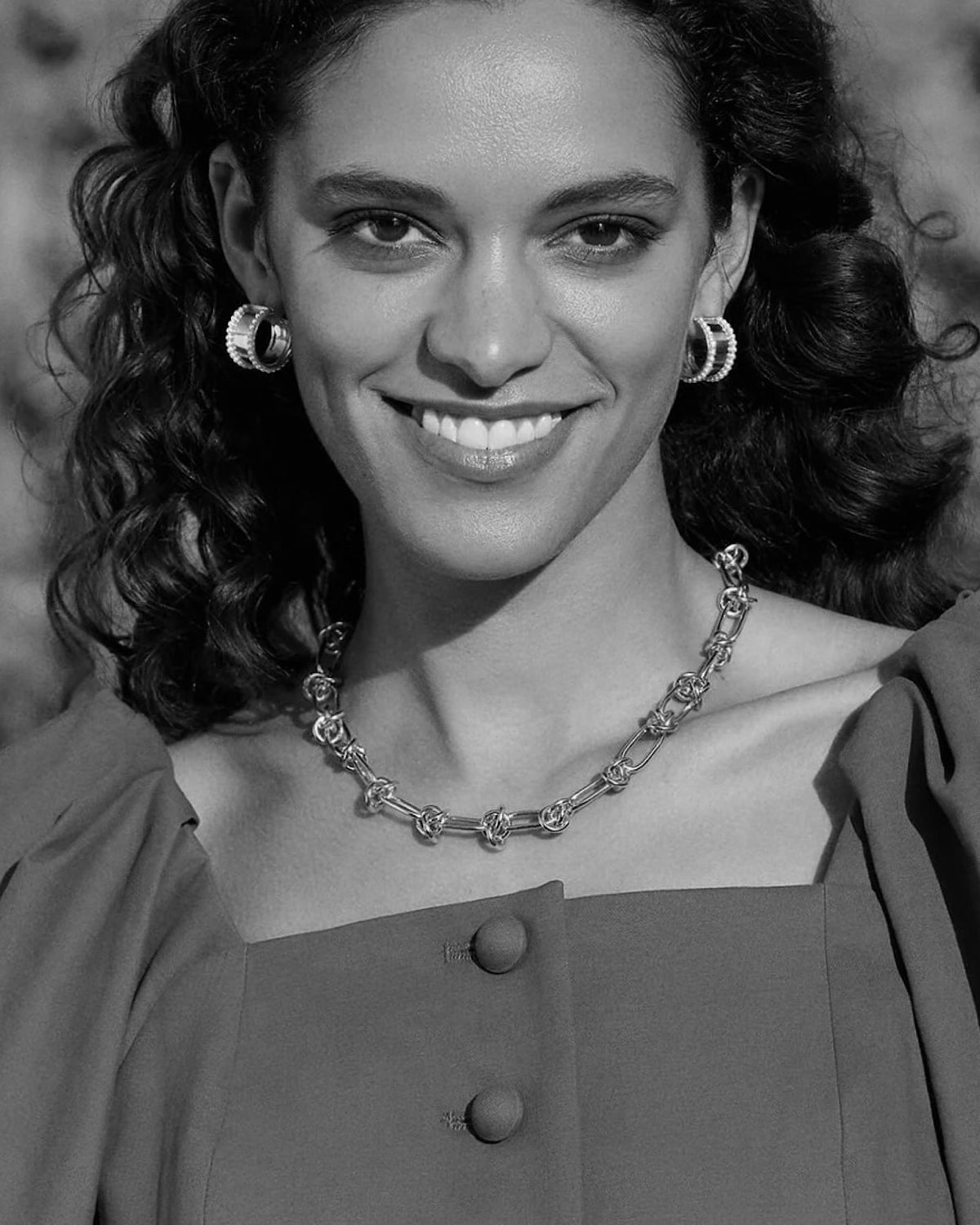 model wears earrings and a link chain necklace