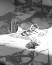 three silver rings sit on marble