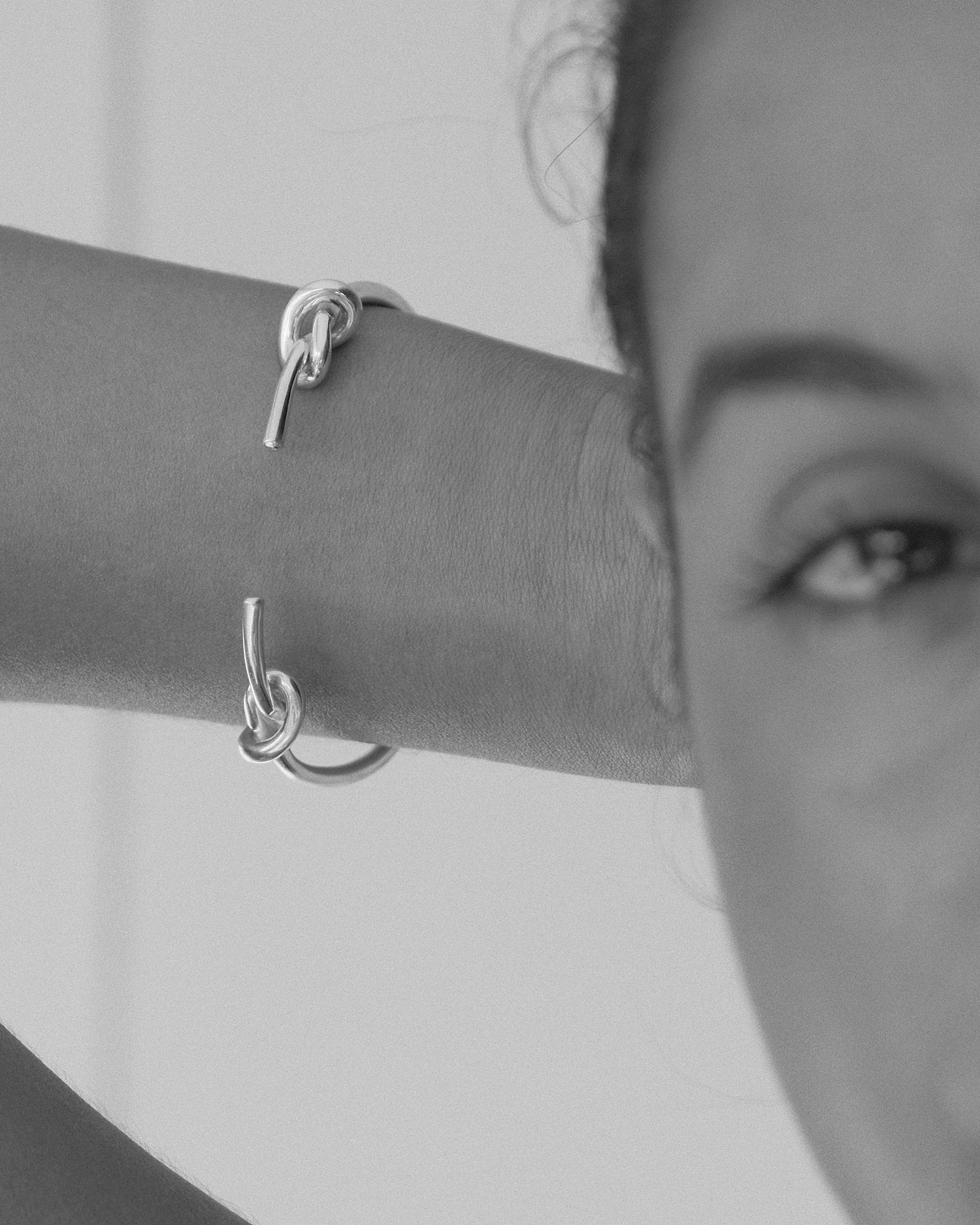 a open cuff bracelet with knots either side sits on an arm