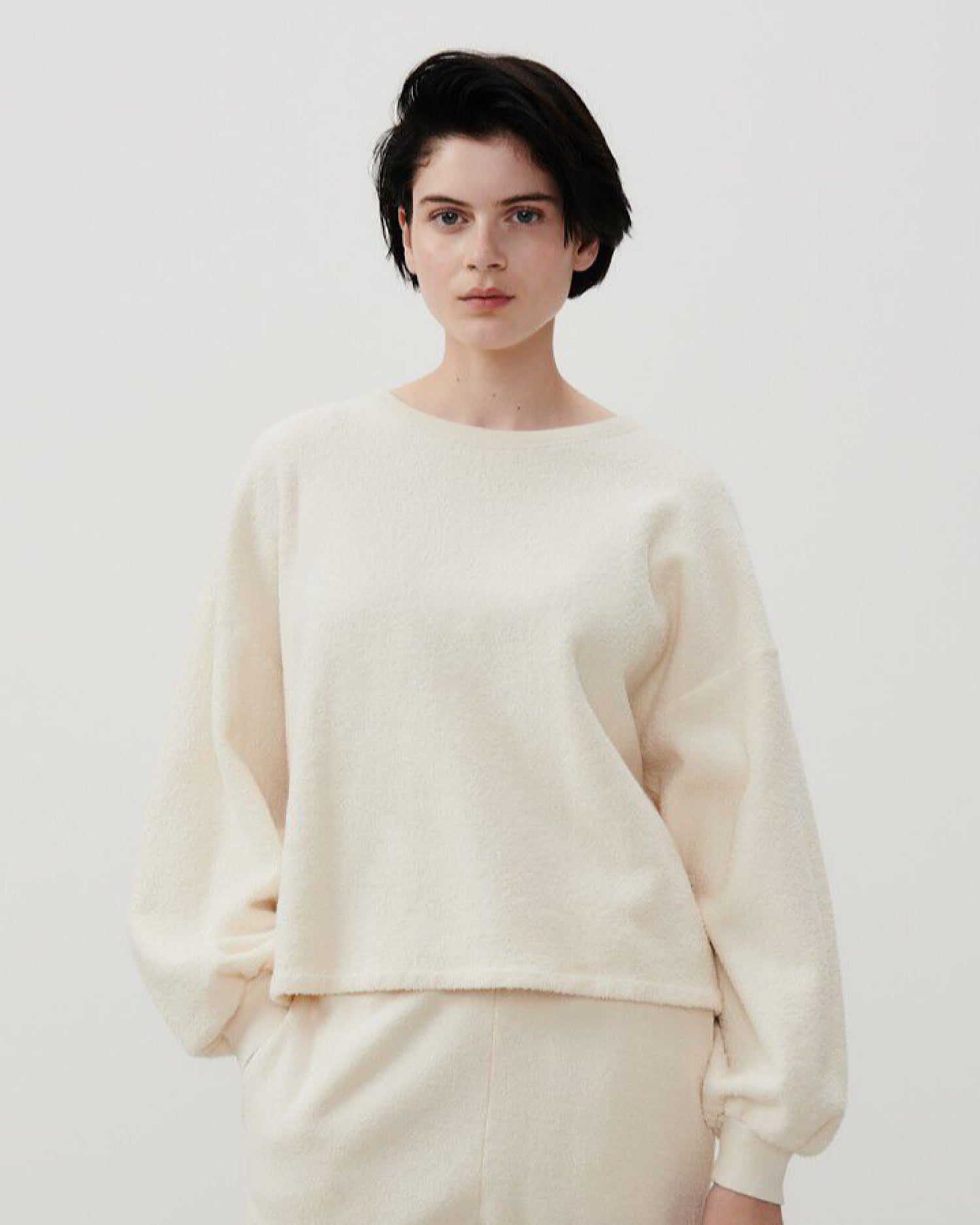 Model wears a cream round neck cotton textured sweater and matching trackpants