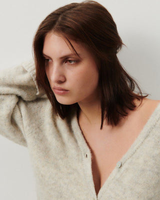 a model wears a cream grey cardigan with a v neck and shell buttons