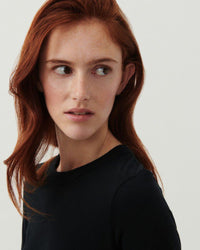 a model wearsa long sleeve black T-Shirt with a high round neck