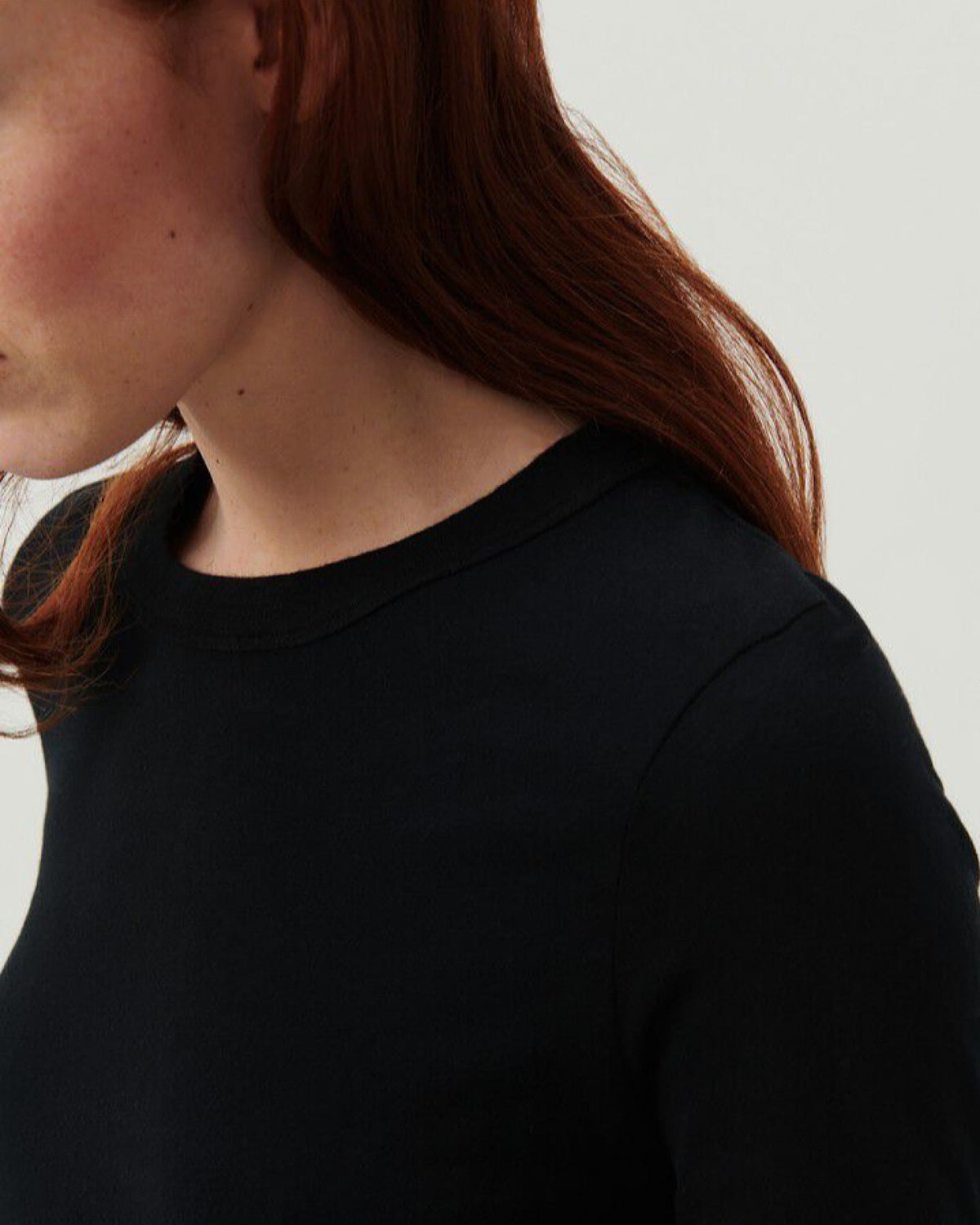 a model wearsa long sleeve black T-Shirt with a high round neck