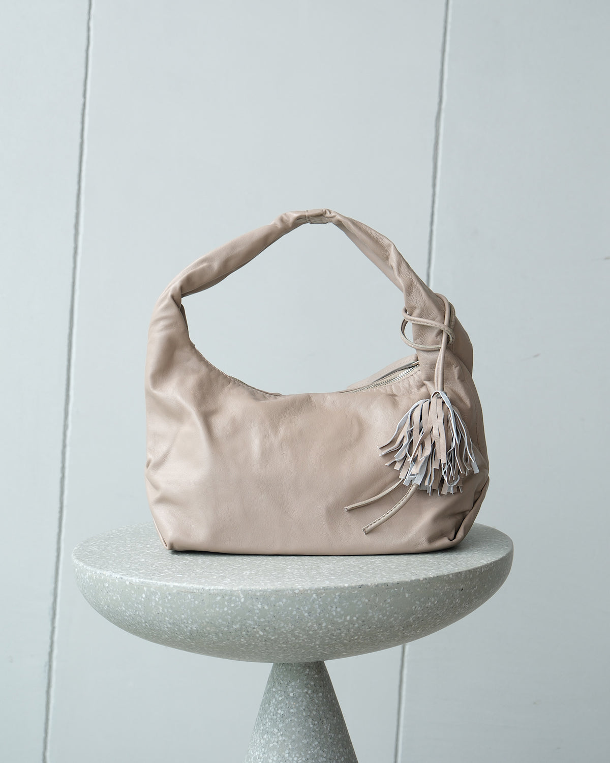 a soft taupe coloured leather bag sits on a stool